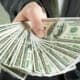 pile of cash in hand reaching out